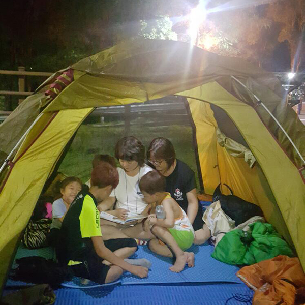 텐트 안에서 책을 읽고 있는 가족 